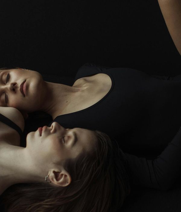Woman in a peaceful yoga pose in a dark studio.